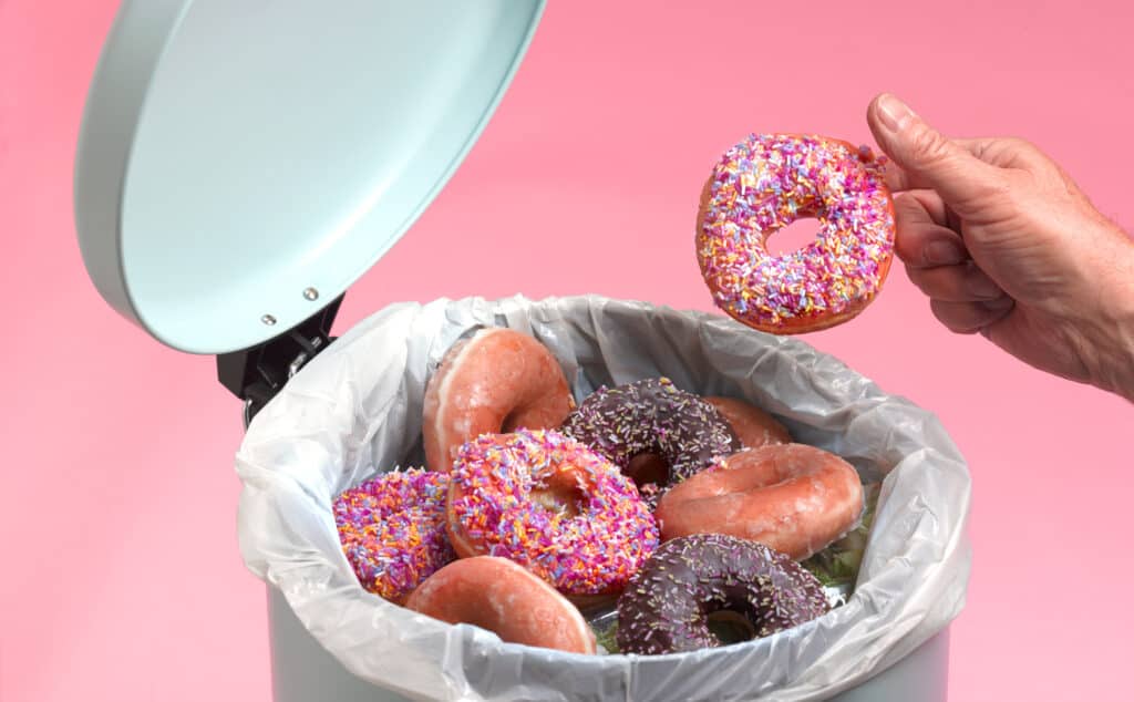 Man throwing donuts in kitchen bin